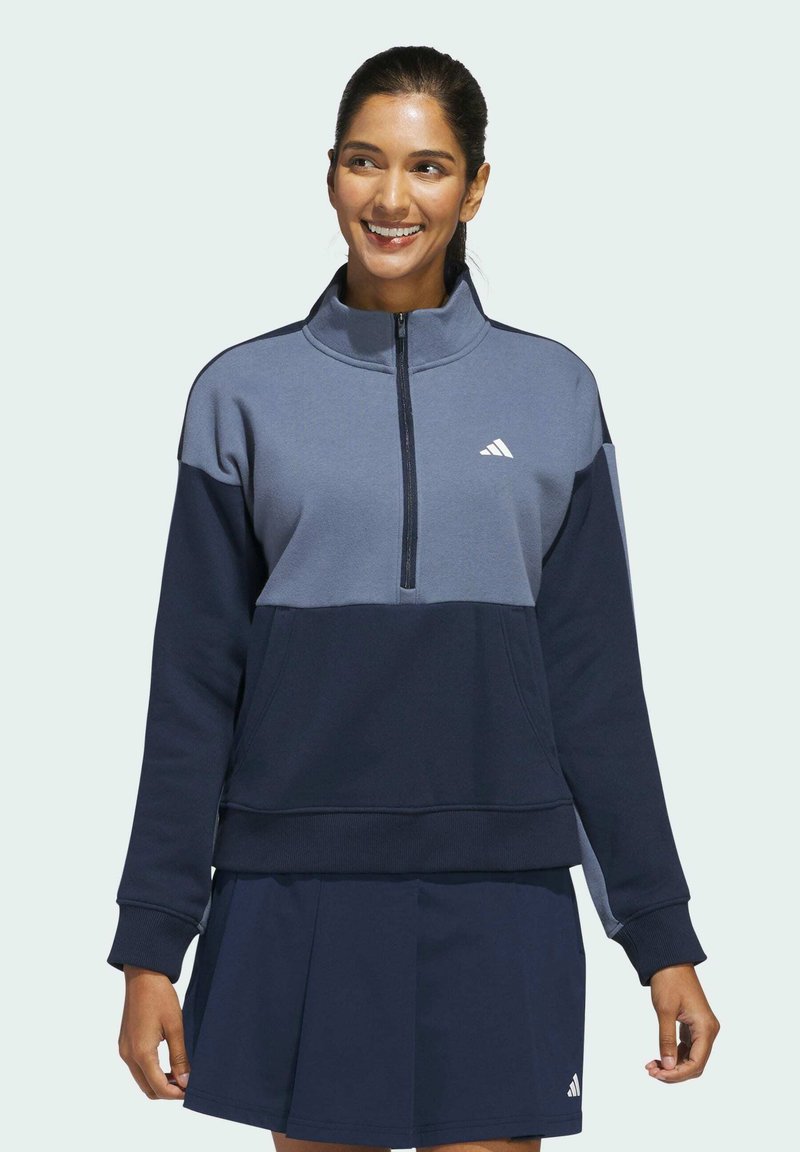 Marineblauwe en grijze sweatshirt met een halve ritssluiting, lange mouwen en zijzakken. Voorzien van een wit logo op de borst en geribbelde manchetten.
