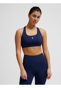 Granatowy biustonosz sportowy z okrągłym dekoltem i szerokimi ramiączkami, w zestawie z granatowymi legginsami o wysokim stanie. Ozdobiony małym białym logo.