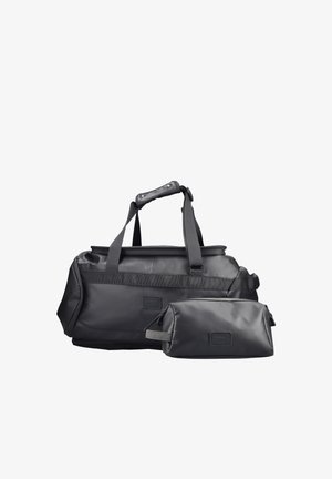 Sac de voyage en cuir noir avec poignée rembourrée et trousse de toilette assortie zippée sur fond blanc.