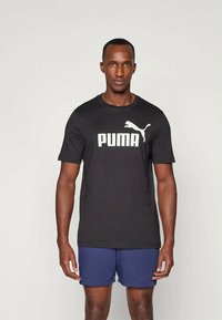 Sort bomulds-t-shirt med korte ærmer, prydet med stort hvidt "PUMA" logo og jaguar grafik på brystet, sammen med marineblå shorts.
