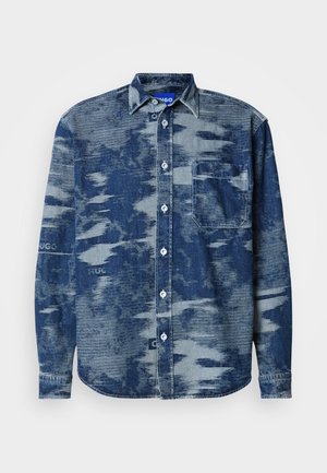 Denimskjorte med et mønstret blå og grå tekstur, knaplukning foran, spids krave og en enkelt brystlomme.