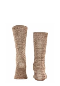 Calze lavorate a maglia in una calda tonalità beige con un pattern testurizzato e melangiato. Presentano una lunghezza alla caviglia e un materiale morbido e traspirante.