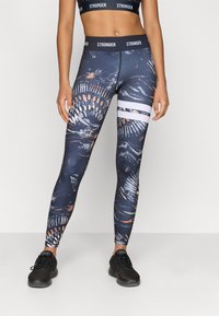 High-waisted leggings in navy with abstract patterns in orange, white, and gray. Features a white stripe on the lower leg and elastic waistband.
