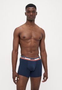 Sötétkék pamut boxer alsónadrág, fehér és piros csíkos derékrésszel, rajta a "Levi's" logo. Sima tapintású és testhezálló kialakítás.