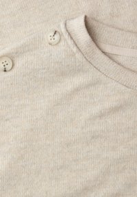 Jasnobeżowy sweter z teksturowanym splotem, okrągłym dekoltem i dwoma dekoracyjnymi guzikami przy ramieniu. Gładkie wykończenie materiału.