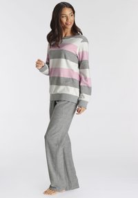 Striped loungewear set featuring a light pink, gray, and white sweater with a round neck and gray pants with side slits, made of soft fabric.