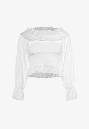 Blouse blanche à manches longues avec corsage smocké, poignets volantés et encolure volantée décorée de fleurs en tissu.