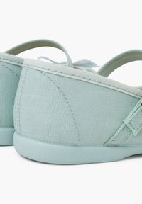 Scarpe slip-on in tela color turchese chiaro con una texture morbida, dotate di tacco curvo e cinghia elastica. I dettagli notevoli includono cuciture decorative.