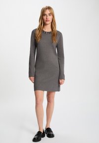 Graues, langärmliges Strickkleid mit Rundhalsausschnitt und beaded Akzent. Das Kleid hat eine taillierte Form und reicht bis zur Mitte des Oberschenkels.