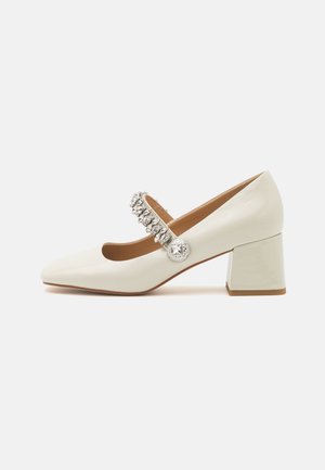 Scarpa Mary Jane bianca in pelle con punta quadrata, tacco medio a blocco e cinturino decorativo argentato abbellito con accenti circolari.