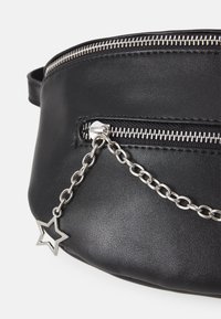 Borsa in pelle nera con una cerniera argentata, dotata di un ciondolo a forma di stella attaccato a una catena. Texture liscia e design minimale.
