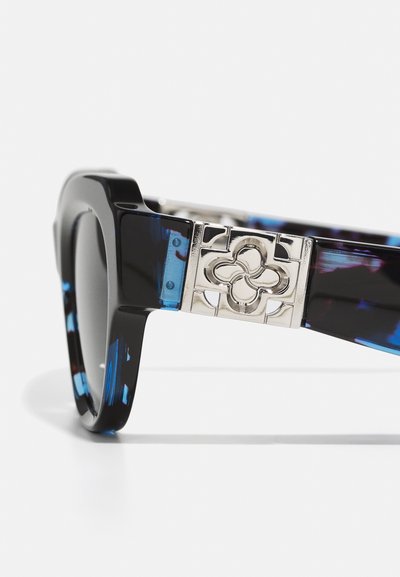 Occhiali da sole neri con una forma quadrata e grossa. Le aste presentano dettagli blu e un motivo floreale argentato. Lenti scure completano il look.