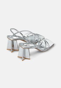 Sandali con tacco argento e punta quadrata, dotati di più sottili fascette. Design del tacco a blocco unico con forma geometrica e dettagli trasparenti.