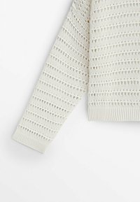 Manche de pull blanc en tricot avec un motif ajouré horizontal et un poignet côtelé sur fond blanc.