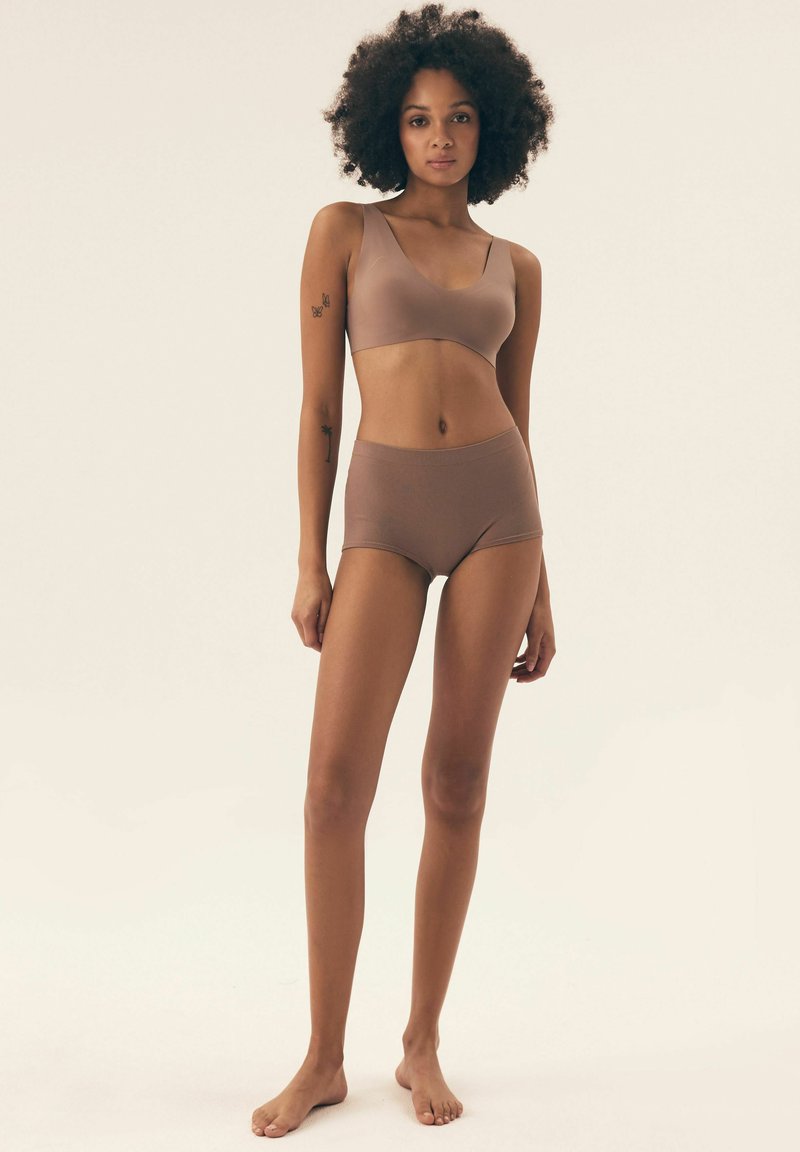 Brązowy, bezszwowy zestaw biustonosza i majtek z wysokim stanem, wykonany z miękkiego, elastycznego materiału. Posiada gładką teksturę i minimalistyczny design.