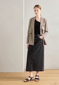 Houndstooth patterned blazer, black tank top, and black denim maxi skirt. Flat black sandals with straps. Wood floor background.