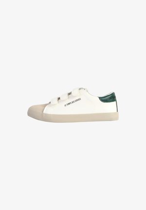 Witte sneaker met een getextureerde groene hiel, crèmekleurige rubberen neuskap en klittenbandsluitingen. Heeft "LE TEMPS DES CERISES" op de zijkant gedrukt.