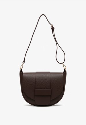 Czarny puszysty sweter dziergany na drutach, szerokie rękawy, dekolt w serek, zestawiony z niebieskimi jeansami i brązową skórzaną torebką na klapę.