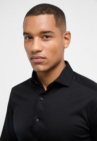 Zwarte overhemd met knoopsluiting, met een klassieke kraag, slim fit en een zachte textuur. Voorzien van zwarte knopen en een gladde afwerking.