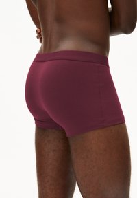 Bordeauxfarbene Boxershorts aus weichem Stoff, mit elastischem Taillenbund und körpernahem Schnitt. Dezente Struktur im Material, nahtlose Verarbeitung.