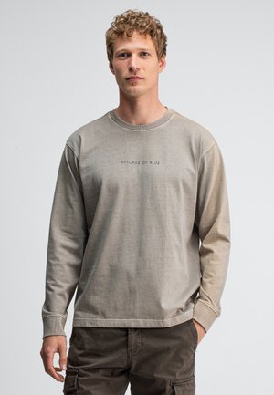 Lange katoenen sweatshirts met lange mouwen in lichtbeige met ribgebreide manchetten. Voorzien van de opdruk "BUTCHER OF BLUE" op de borst. Ontspannen pasvorm.