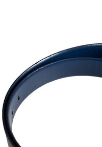 Blå læderbælte med en glat overflade, afrundede kanter og flere justeringshuller. Indersiden viser et subtilt prægninger.