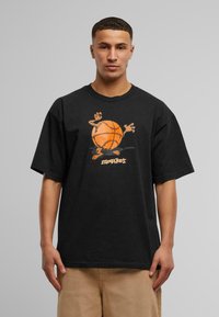 Svart bomullströja med korta ärmar, med en orange basketboll och karaktärsgrafik på framsidan. Avslappnad passform med rund hals.