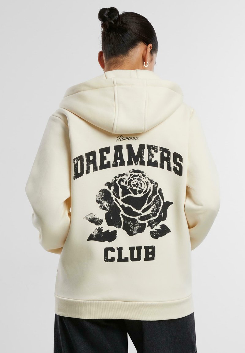 Cremefarbener Hoodie mit einem schwarzen Rosenmotiv und dem Text "DREAMERS CLUB" auf dem Rücken, ausgestattet mit einer Kapuze und gerippten Bündchen.