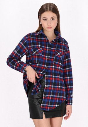 Red, blue, and white checkered flannel shirt with long sleeves, two chest pockets, and buttons; paired with a black leather mini skirt.