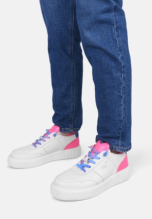 Sneakers bianchi con dettagli rosa e blu, tessuto texturizzato, punta rotonda e suola in gomma spessa, abbinati a jeans di denim blu.