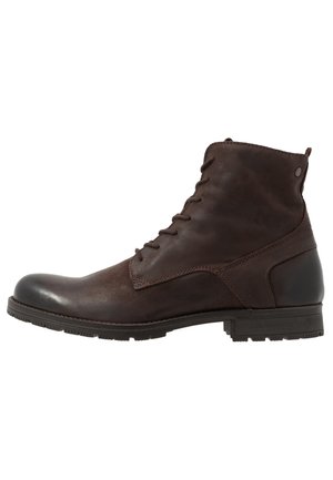 Bottine montante en cuir marron foncé à lacets, avec un petit talon et une semelle en caoutchouc texturée, montrée de profil sur fond blanc.