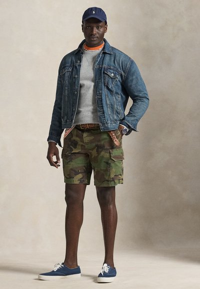 Τζιν μπουφάν, γκρι φούτερ, καμουφλαρισμένες cargo βερμούδες, μπλε αθλητικά και μπλε σκουφάκι. Διαθέτει υφάσματα με υφή και ένα casual, πολύστιχο σχέδιο.