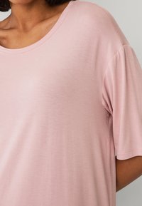 Lys rosa kortærmet t-shirt med rund halsudskæring, lavet af blødt stof. Den har en afslappet pasform og en subtil tekstur.