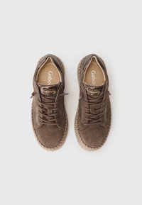 Brune semskede snørestøvler med teksturert side, en beige gummisåle og en dekorativ utsmykning på tungen.