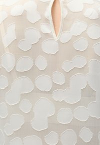 Διαφανές πουκάμισο με υφασμένους λευκούς κυκλικούς σχεδιασμούς και μικρό κάθετο άνοιγμα στην λαιμόκοψη.