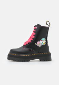 Botas de cuero negras con cordones de un brillante color rosa, suela de plataforma y parches de dibujos animados coloridos en el costado. Presentan costuras en contraste y una pestaña para tirar.