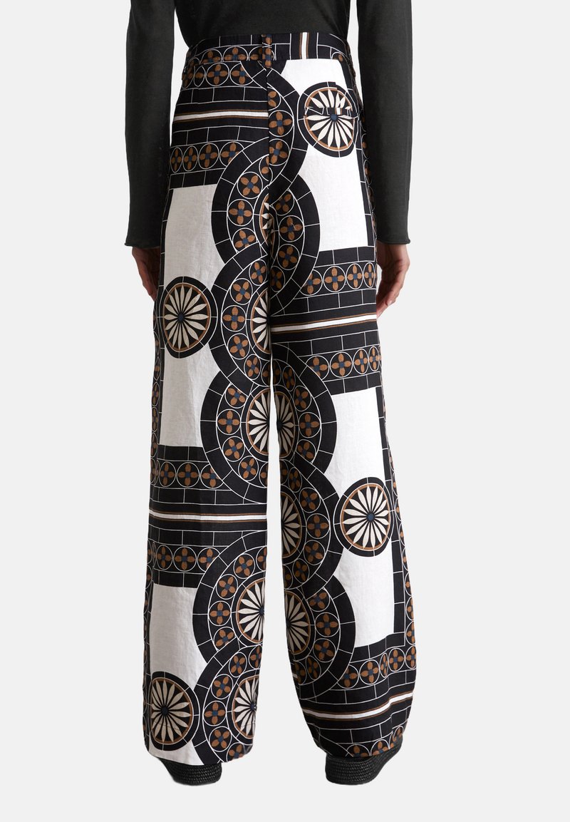 Pantaloni a gamba ampia con un motivo geometrico in nero, bianco e ruggine. Tessuto in cotone con una texture liscia e design a vita alta.