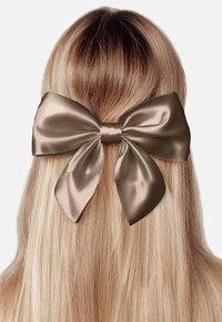 Satinschleife in einem sanften Taupe-Ton, mit einem großen, strukturierten Design, breiten Schlaufen und einem mittigen Knoten, die glattes blondes Haar schmückt.