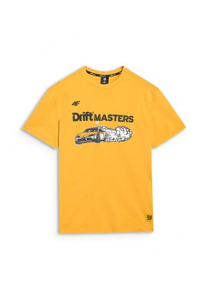 Mężczyzna w żółtej koszulce z napisem „Drift Masters” i grafiką samochodu driftującego, w czarnych szortach na jednolitym tle.