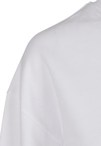 Baltas medvilninis marškinėlis su apvalia iškirpte, trumpomis rankovėmis ir lygiu audiniu, laisvo kirpimo. Tinka kasdieniam dėvėjimui.