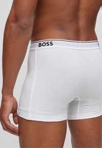 Weiße Boxershorts aus Baumwolle mit einem schwarz-weißen Gummibund, der mit "BOSS" beschriftet ist. Enganliegendes Design, glatte Textur.