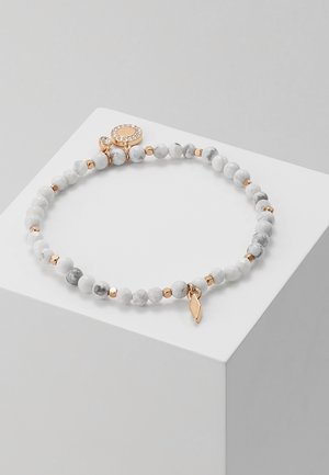 Bracelet extensible avec perles marbrées blanches, petites perles intercalaires en or, un pendentif en forme de losange en or, et un fermoir rond en or orné de strass.