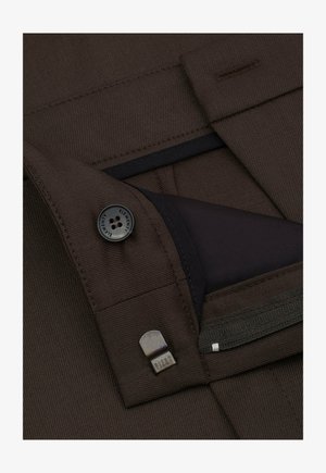 Brązowy materiał tekstylny o fakturowanym wykończeniu, z czarnym guzikiem oraz kieszenią na zamek z gładką, ciemną podszewką i metalicznym akcentem.