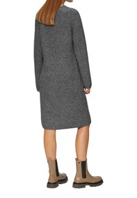 Grijze gebreide trui jurk met lange mouwen, geribbelde textuur en middellange snit, gecombineerd met beige enkellaarsjes met elastische panelen.