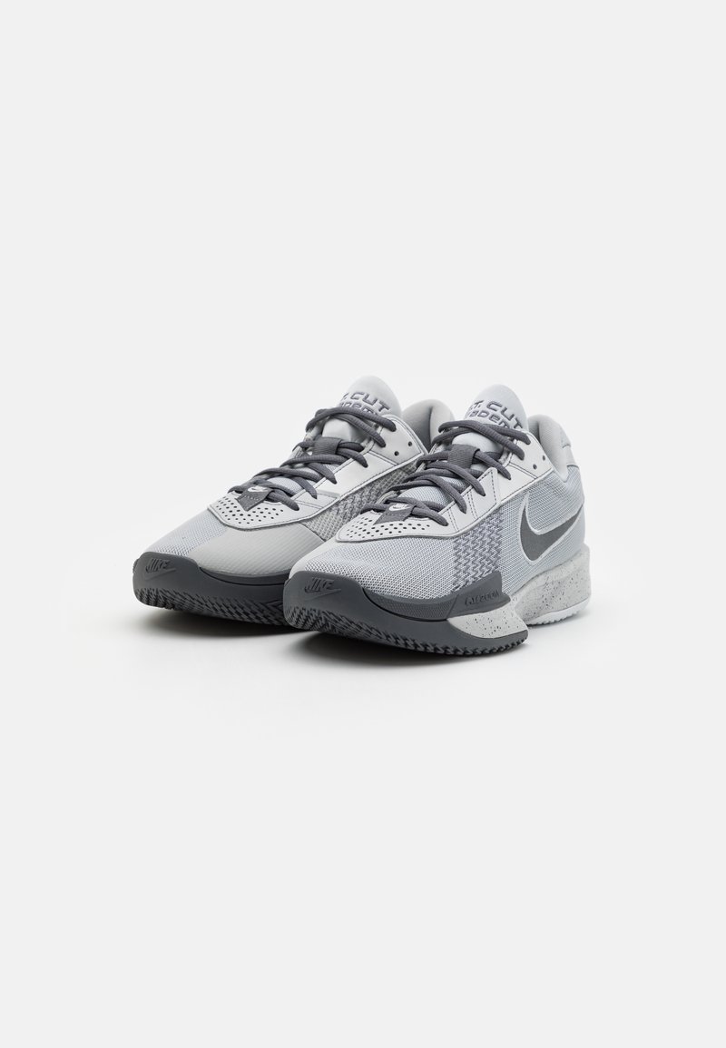 Une paire de baskets Nike grises et blanches avec des semelles et des lacets noirs, affichée côte à côte sur un fond blanc.