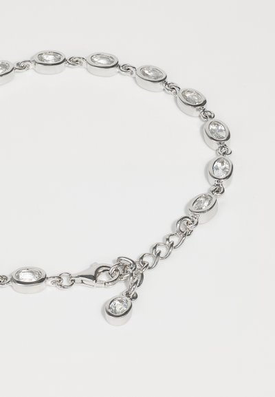 Silver chain bracelet featuring oval clear gemstones set in metal links, with a clasp and extra charm on the adjustable chain.