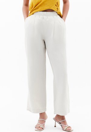 Pantalones de pierna ancha en gris claro con cintura elástica, que presentan pliegues frontales y bolsillos laterales. Tela suave y fluida, con dobladillo en los tobillos.