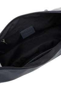 Must nahast koti sisemus sileda tekstuuriga, lukuga tasku ja bränditud sildiga. Musta riidega vooderdatud, et lisada kontrasti.