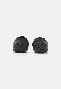 Black athletic shoes with a textured fabric upper, thick rubber soles, and a geometric tread pattern. Features "MERRELL" branding on the heel.