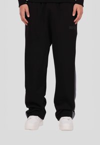 Czarne spodnie dresowe wykonane z miękkiego materiału, charakteryzujące się prostym krojem nogawki i elastycznym pasem. Subtelne logo marki po boku.
